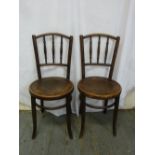 A pair of bentwood kitchen chairs with circular seats and outswept legs