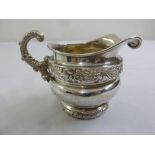 A Georgian silver cream jug with scroll handle on raised circular base, marks rubbed