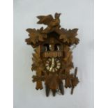 Black Forest cuckoo clock profusely carved with birds and leaves to include three weights and