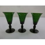 Three Victorian green glass cordial glasses on raised circular bases
