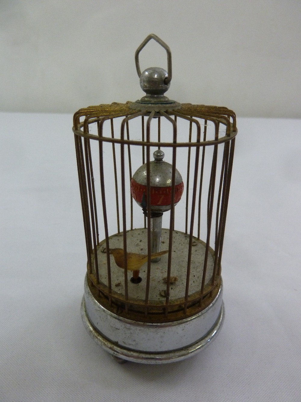 An automation clock with bird in a cage with carrying handle on circular base