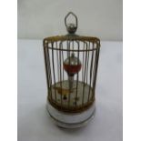 An automation clock with bird in a cage with carrying handle on circular base