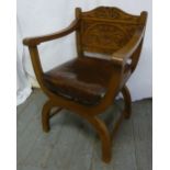 An Elizabethan style light oak armchair with carved scroll and leaf back and leather seat