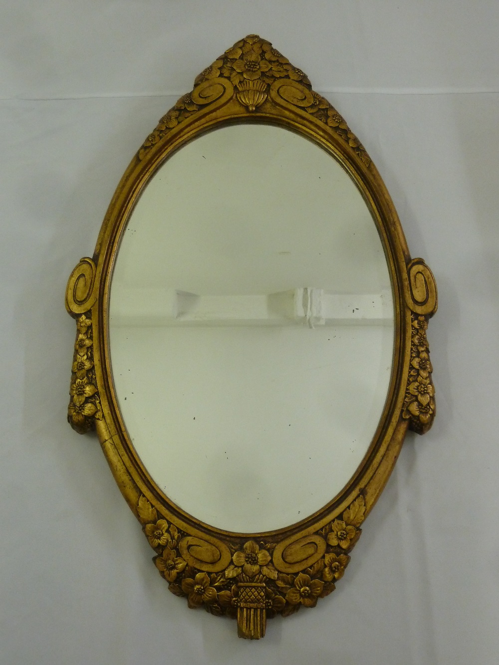 A shaped oval gilded wooden wall mirror