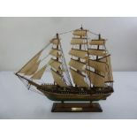A wooden model of the Cutty Sark with linen sails mounted on a wooden plinth