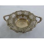 A silver two handled circular dish with pierced sides with leaf decorations and scalloped border,