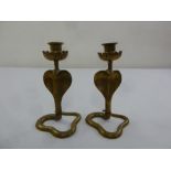 A pair of brass candlesticks in the form of striking cobras