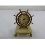 An Estyma ships wheel clock on raised square onyx base with four gilt metal feet