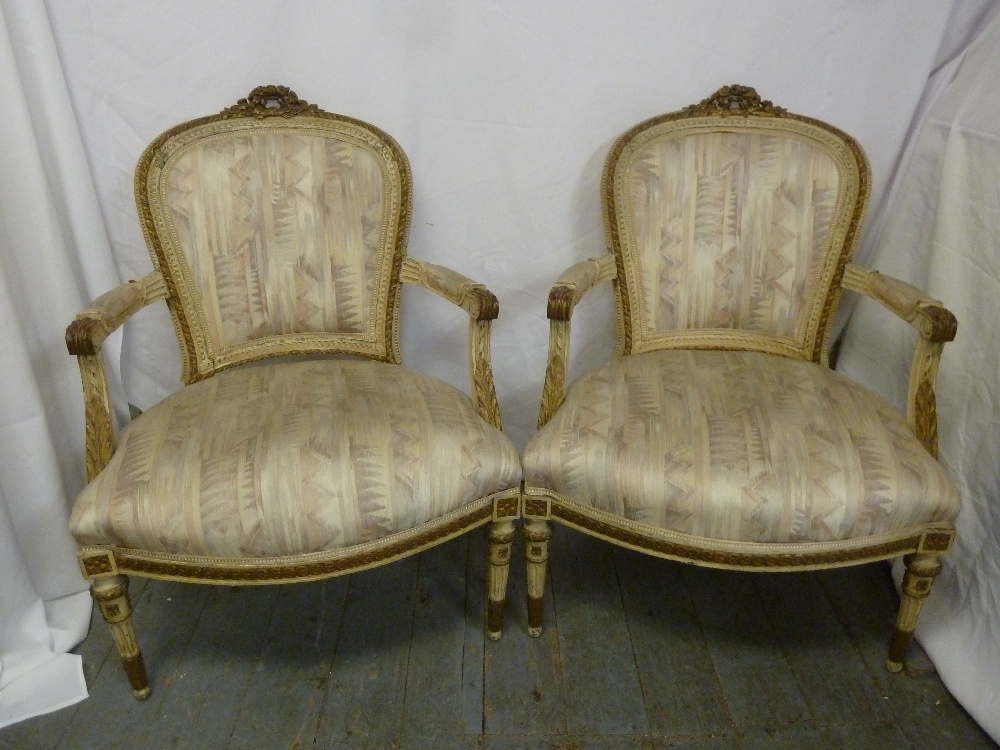 A pair of French upholstered armchairs on turned tapering cylindrical legs