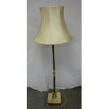 A brass and onyx standard lamp on square base with four brass feet to include silk shade