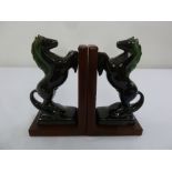 A pair of black glass horse figurines mounted on leather bookends