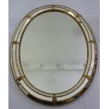An oval wall mirror with raised decorative mirror and gilt metal frame