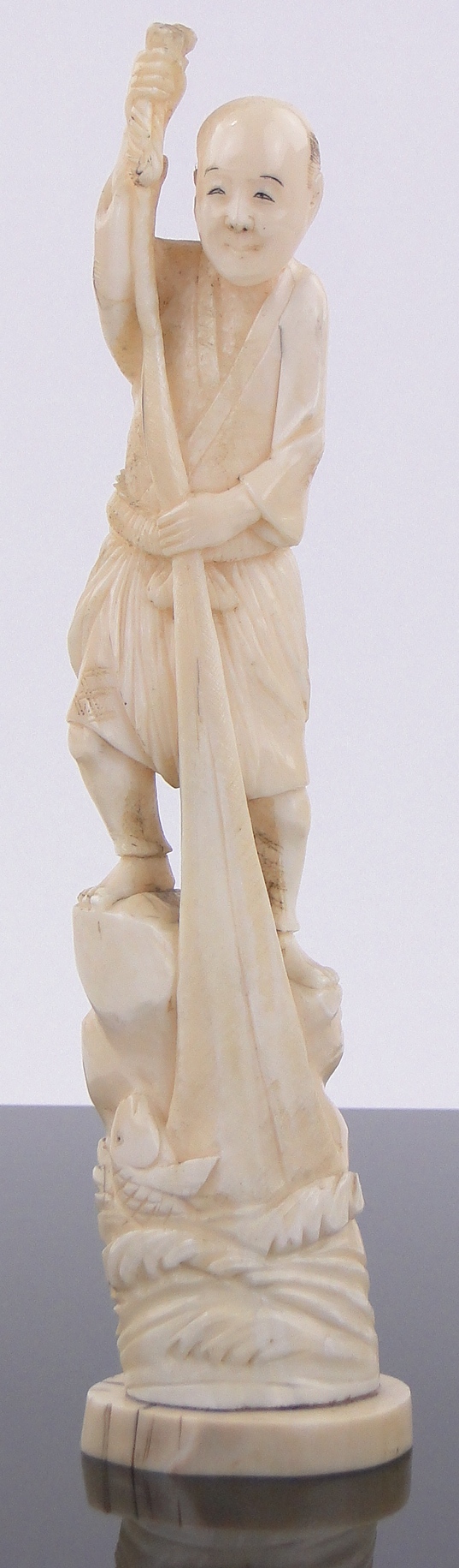 A 19th century Chinese carved ivory figure of a fisherman, signed under base, height 9".