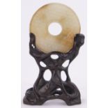 A Chinese carved jade disc, diameter 2" on original carved wood stand.