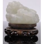 A Chinese carved white jade dragon, carved hardwood stand, length 2.5".