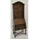 A 1920s oak bureau bookcase, having a carved arch top with lead light glazed door,