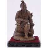 A Chinese carved stained wood figure of a seated man, height 7" on carved wood plinth.