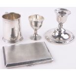 A group of silver items, including christening mug, cigarette case, eggcup and candlestick, (4).