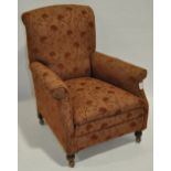 An Edwardian upholstered armchair with turned bun feet.
