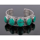 A heavy South East Asian unmarked silver filigree bangle, set with graduated turquoise.