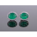 Pair of platinum, emerald and diamond oval cluster earrings, length 12mm.