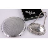A circular silver compact, silver whisky decanter label and brooch, (3).
