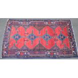 A red ground Persian wool rug with symmetrical pattern and border, 9' x 5'2".