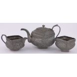 An unmarked Indian white metal 3-piece teaset, ornately chased and embossed floral decoration,