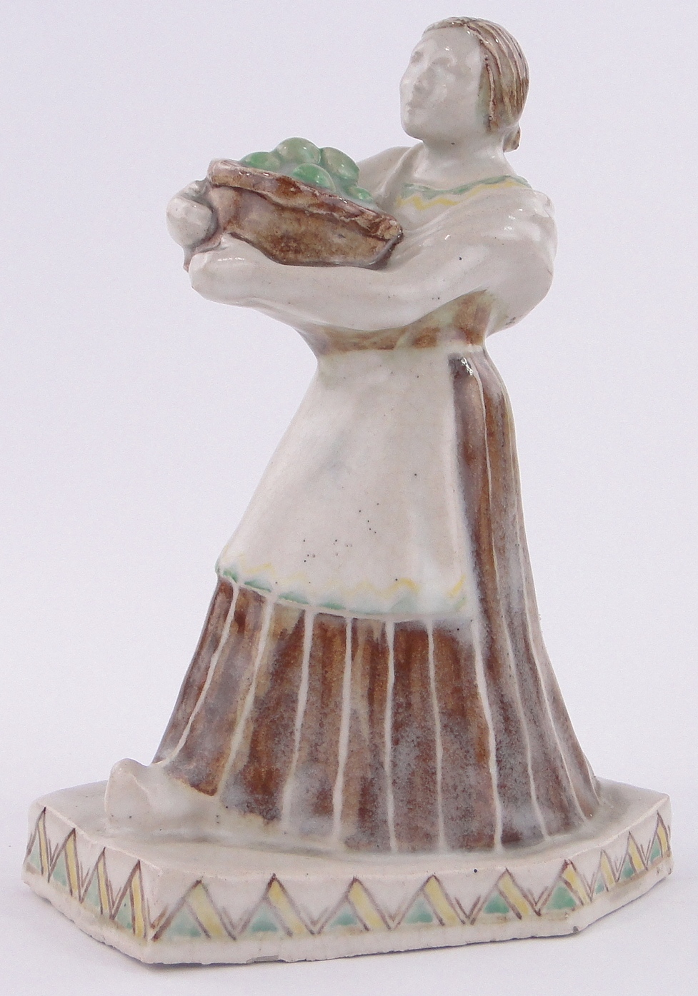 A glazed Studio Pottery figure of a woman carrying a basket of fruit,