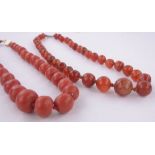 A string of graduated coral beads circa 1900, and a Cornelian bead necklace, (2).