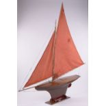 An early to mid 20th century wooden hull Gamages London pond yacht, with mast and sails,