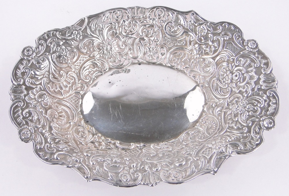 A Victorian oval silver bowl, with relief decorated flowers and scrolls by William Comyns,