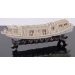 A Chinese carved ivory pleasure boat, early 20th century, length 22cm on carved hardwood stand.
