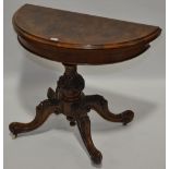 A Victorian figured walnut demi lune card table, raised on a carved sabre leg base.