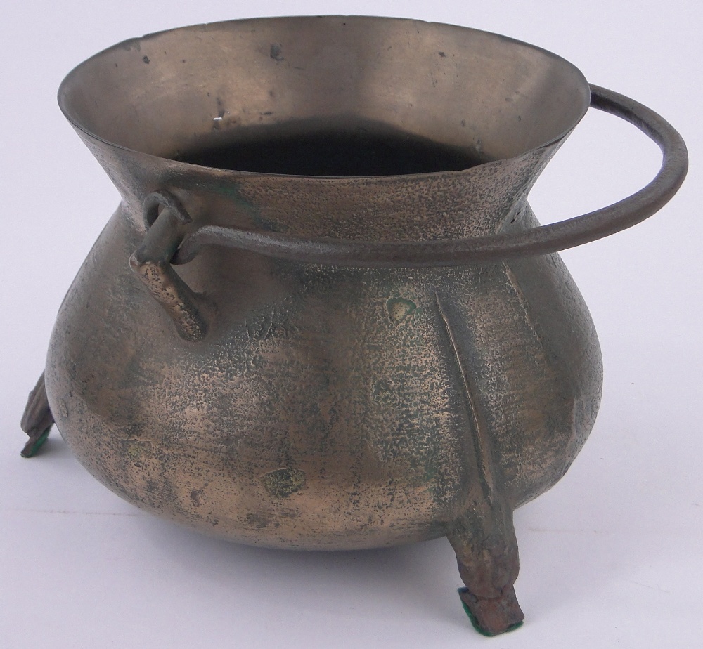 A bronze cauldron, 17th/18th century with flared rim, iron swing handle on 3 feet,