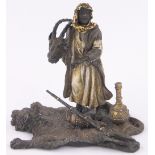 A cold painted bronze Arab huntsman standing on a tiger's skin rug, length 16cm, height 15cm.