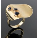 An unusual 18ct gold serpentine disc shaped designer ring, set with 3 graduated pear-cut sapphires,