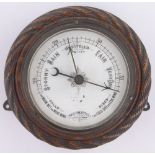 A Victorian carved oak cased aneroid wall barometer, with ropetwist surround, diameter 18cm.