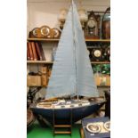 A model pond yacht with sails, on wooden stand.