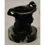A small bronze pot with floral design on marble plinth.