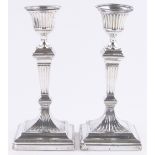 A pair of Victorian square section fluted silver candlesticks, London 1898, weighted bases,