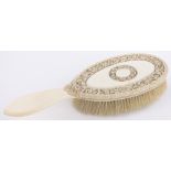 A Chinese ivory backed hand brush, circa 1900, the back intricately carved with entwined flowers,