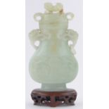 A Chinese pale green jade vase and cover, relief carved allover with dragons and scrolls,