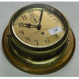 A brass California standard bulkhead clock with oak mounting plaque.