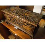 A small dragon carved stained wood box with rising lid on turned feet.