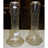 A pair of tall glass vases with silver rims.