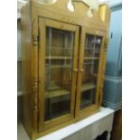 A polished pine bookcase top with 2 glazed doors.