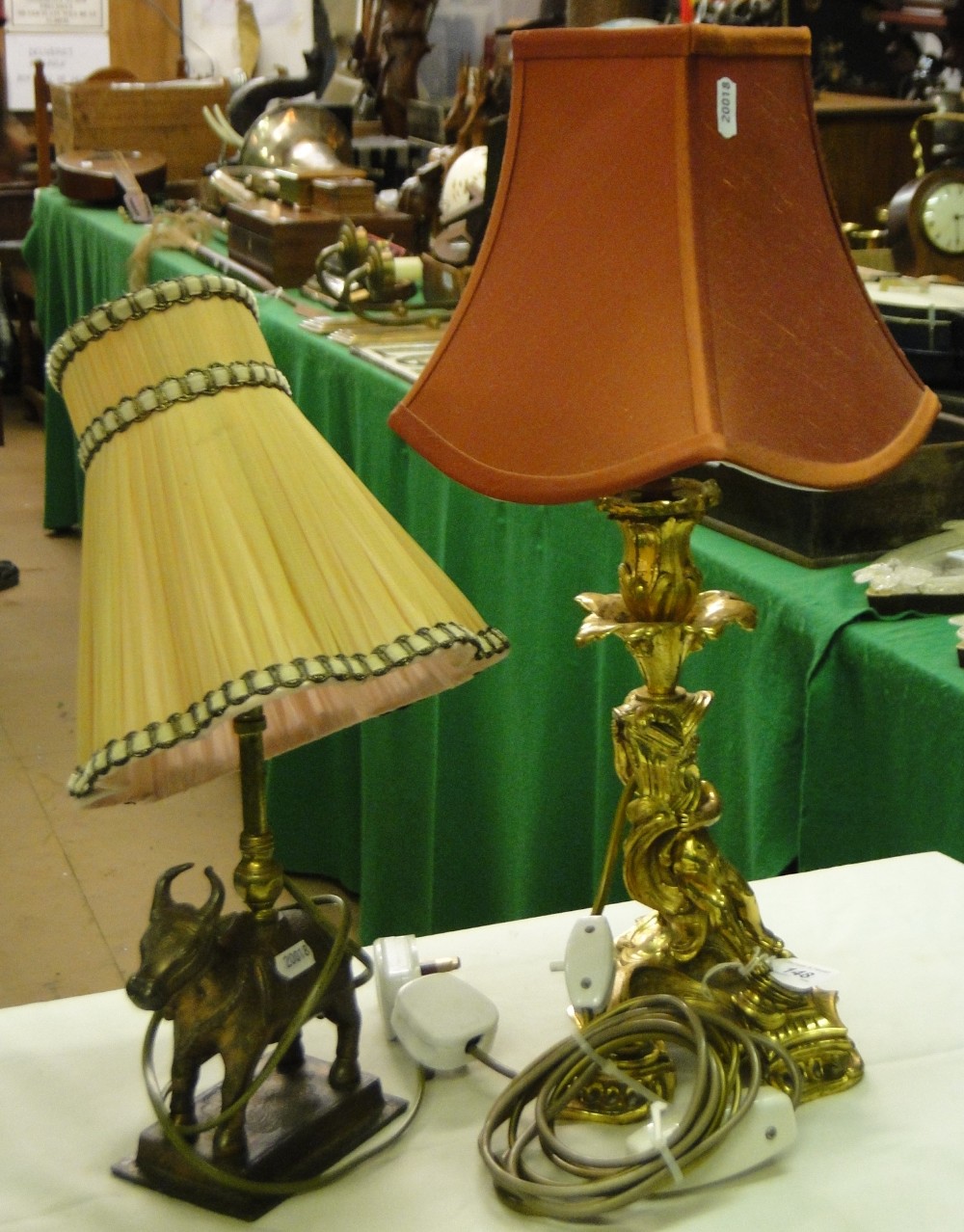 A gilt brass table lamp with cherub support and an Eastern brass table lamp with cow figure.
