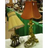 A gilt brass table lamp with cherub support and an Eastern brass table lamp with cow figure.