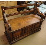 A carved and panelled oak bench with rising seat, length 3'4".